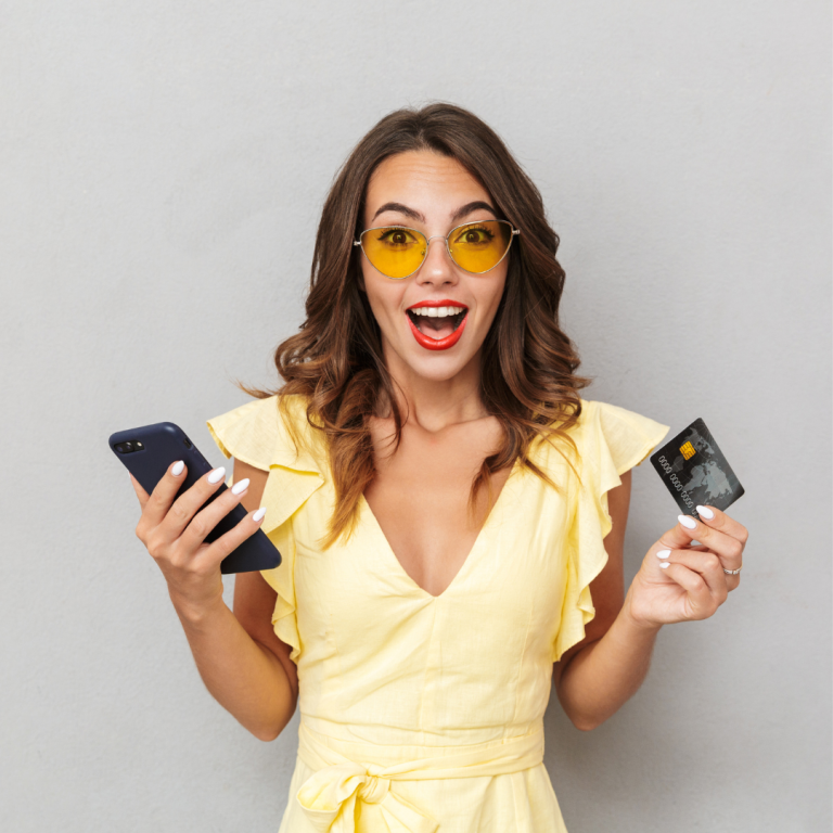 Mujer emocionada solicitando créditos de Cajamag con su tarjeta y teléfono móvil